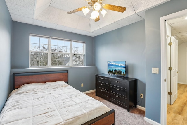 carpeted bedroom featuring a drop ceiling and ceiling fan