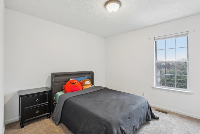 bedroom featuring light colored carpet, multiple windows, and a textured ceiling