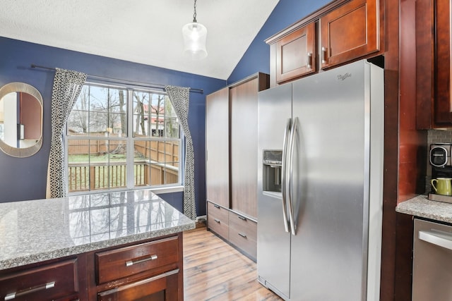 kitchen featuring appliances with stainless steel finishes, light stone counters, decorative light fixtures, vaulted ceiling, and light wood-type flooring