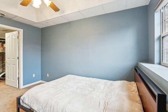 bedroom with carpet floors, a drop ceiling, and ceiling fan