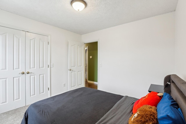 carpeted bedroom with a closet and a textured ceiling