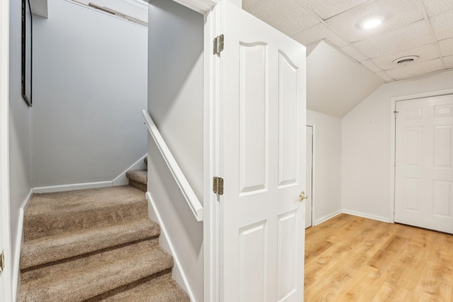 stairs with carpet flooring and a drop ceiling