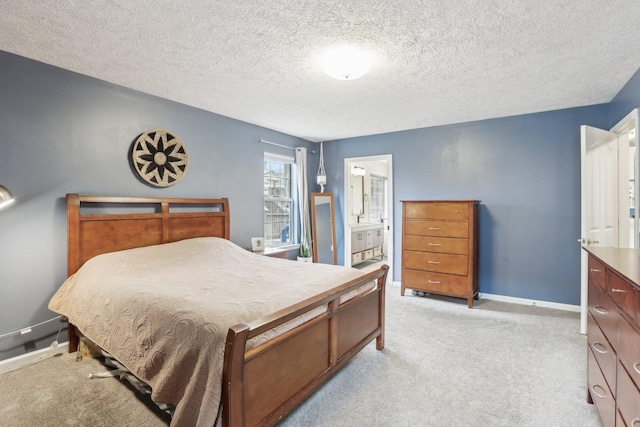 bedroom with ensuite bath, light carpet, and a textured ceiling