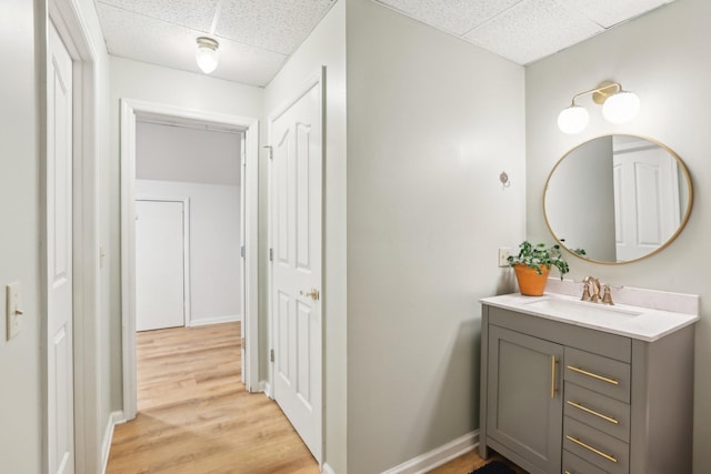 bathroom with hardwood / wood-style flooring, vanity, and a paneled ceiling