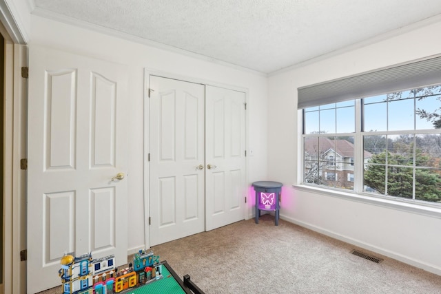 recreation room featuring crown molding, carpet flooring, and a textured ceiling