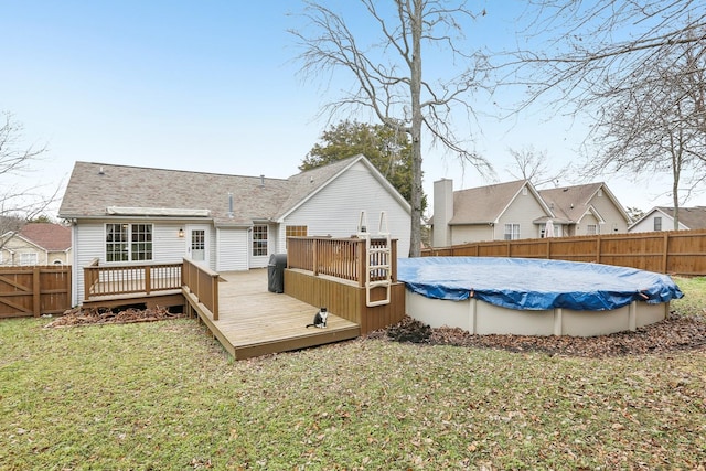 back of house with a pool side deck and a yard