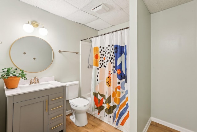 bathroom featuring hardwood / wood-style flooring, vanity, toilet, and a drop ceiling