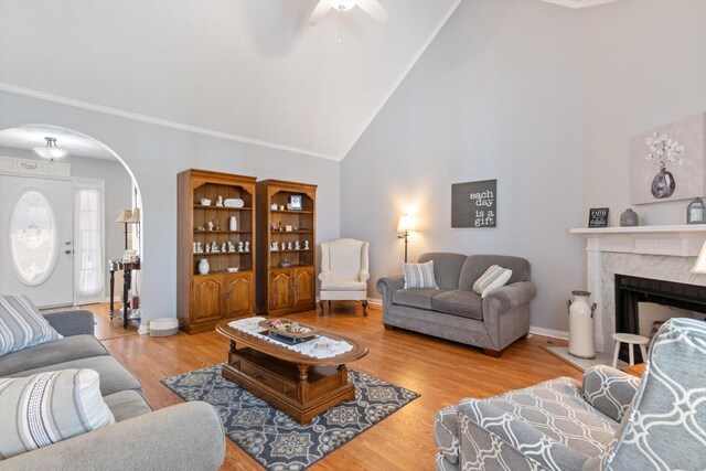 living room featuring a premium fireplace, wood-type flooring, high vaulted ceiling, and crown molding