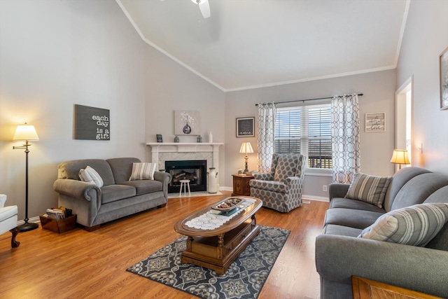 living room featuring high vaulted ceiling, wood-type flooring, ornamental molding, and a premium fireplace