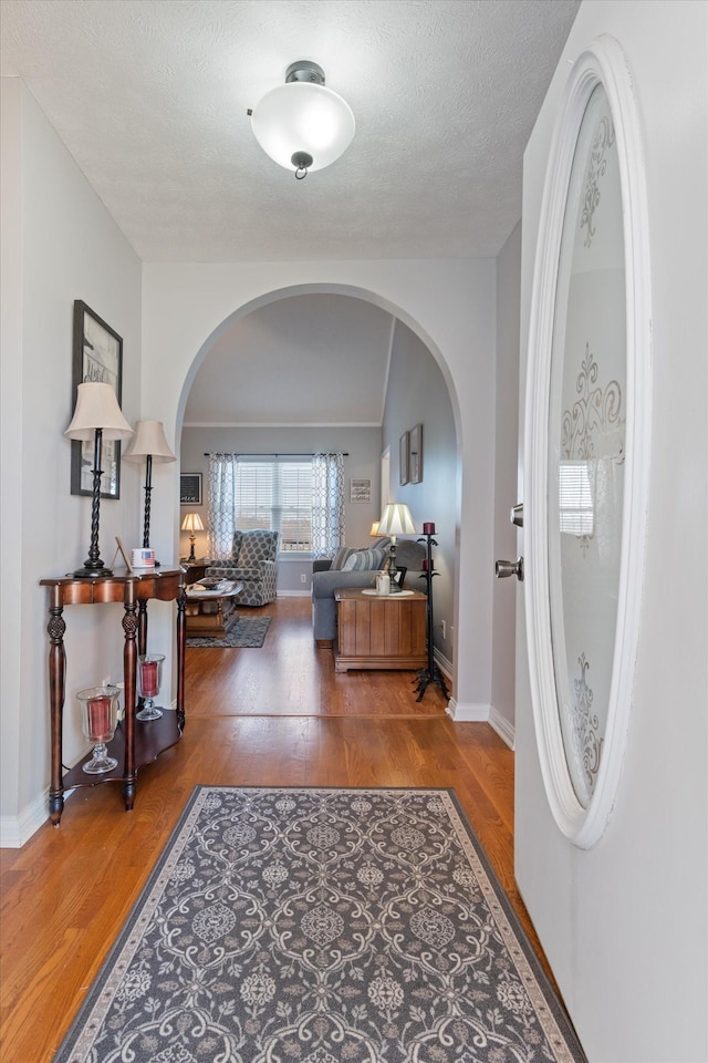 interior space with hardwood / wood-style floors, vaulted ceiling, and a textured ceiling