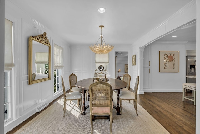 dining space featuring ornamental molding, a chandelier, and wood-type flooring