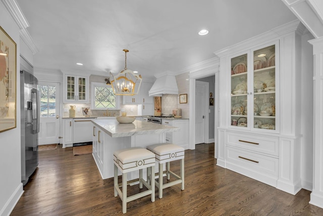 kitchen featuring white dishwasher, decorative light fixtures, custom exhaust hood, and white cabinetry