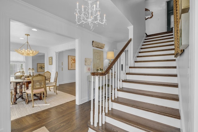 stairs featuring an inviting chandelier, hardwood / wood-style flooring, and ornamental molding