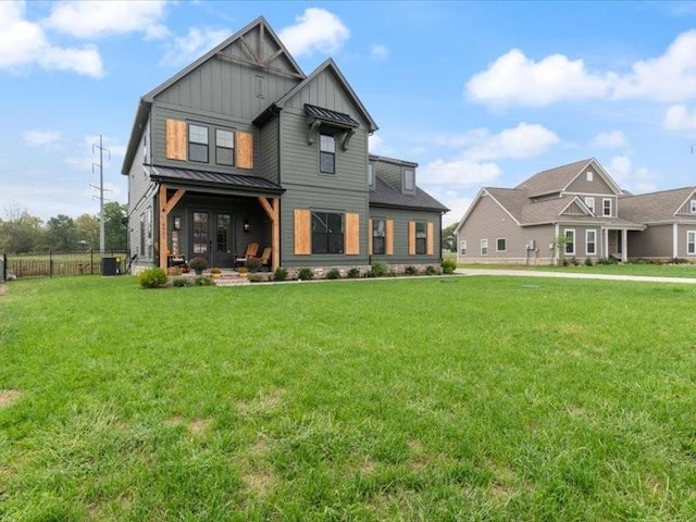 rear view of property featuring central AC and a lawn