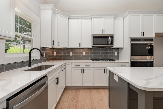 kitchen with white cabinetry, appliances with stainless steel finishes, backsplash, and a sink