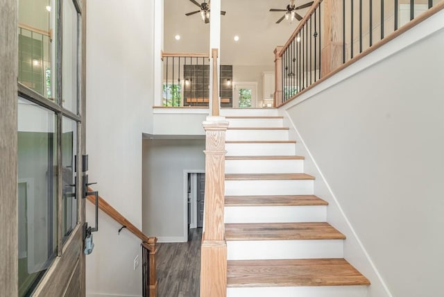 staircase with recessed lighting, a high ceiling, a ceiling fan, wood finished floors, and baseboards