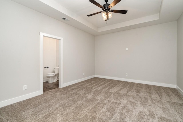 unfurnished bedroom with carpet floors, a raised ceiling, visible vents, and baseboards