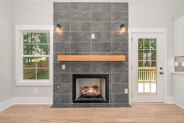 details with wood finished floors, a tile fireplace, and baseboards