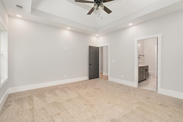 unfurnished bedroom with recessed lighting, light colored carpet, visible vents, baseboards, and a raised ceiling