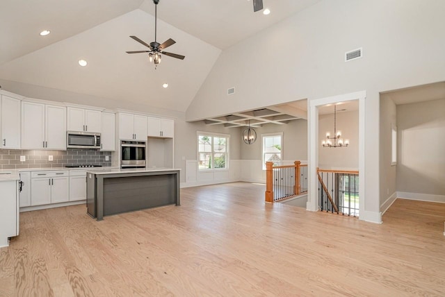 kitchen with light wood finished floors, white cabinets, appliances with stainless steel finishes, open floor plan, and a center island