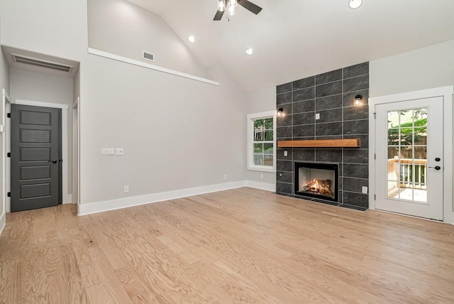 unfurnished living room featuring visible vents, plenty of natural light, a tiled fireplace, and wood finished floors