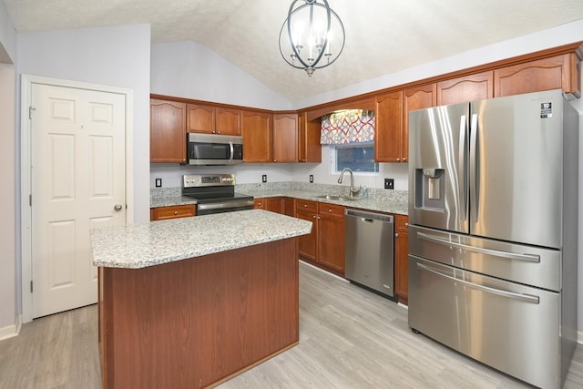 kitchen with pendant lighting, a kitchen island, vaulted ceiling, and appliances with stainless steel finishes