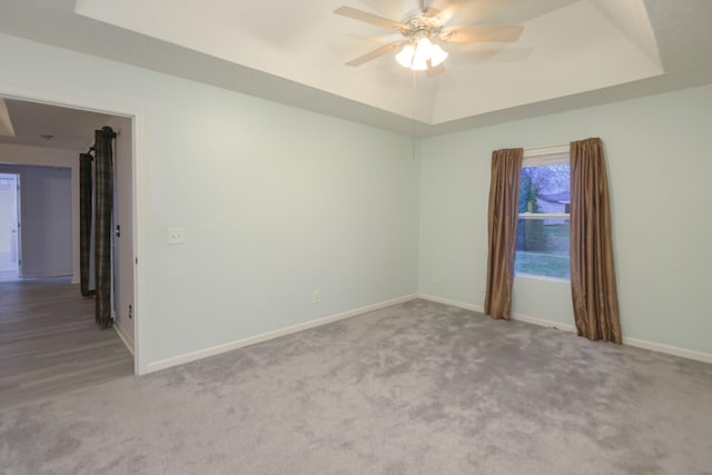 unfurnished room with carpet floors, a raised ceiling, and ceiling fan