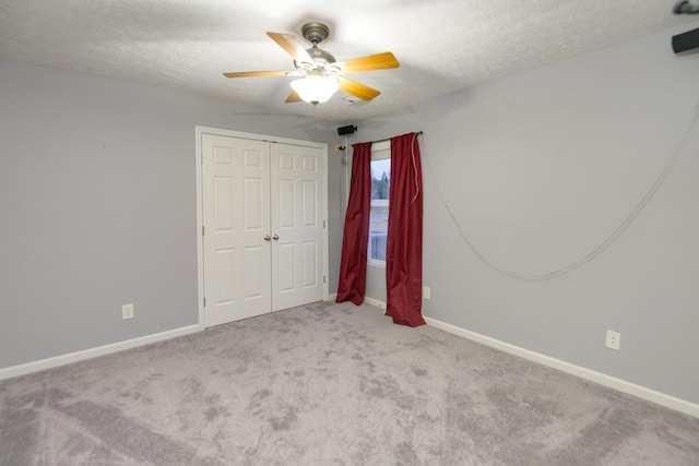 unfurnished bedroom featuring ceiling fan, a closet, light carpet, and a textured ceiling