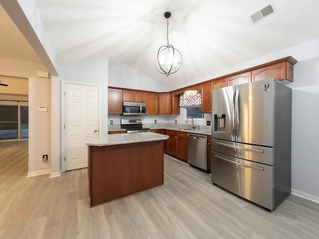 kitchen with a kitchen island, appliances with stainless steel finishes, sink, hanging light fixtures, and light stone countertops