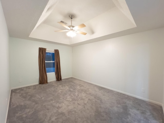 carpeted empty room featuring ceiling fan and a raised ceiling