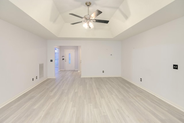 unfurnished room with ceiling fan, a raised ceiling, and light hardwood / wood-style flooring