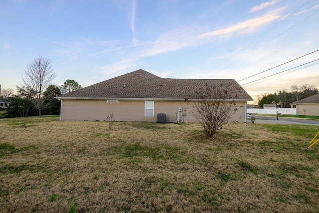 property exterior at dusk with a yard and central air condition unit