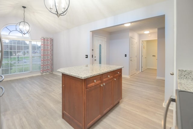 kitchen featuring decorative light fixtures, a kitchen island, a notable chandelier, light stone countertops, and stove