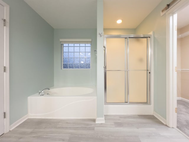 bathroom with wood-type flooring and shower with separate bathtub