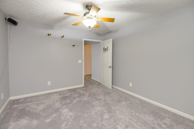 spare room with ceiling fan, light colored carpet, and a textured ceiling