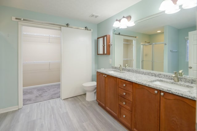 bathroom with a shower with door, vanity, wood-type flooring, and toilet