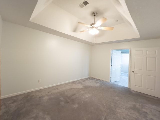 unfurnished room with ceiling fan, a tray ceiling, and carpet floors