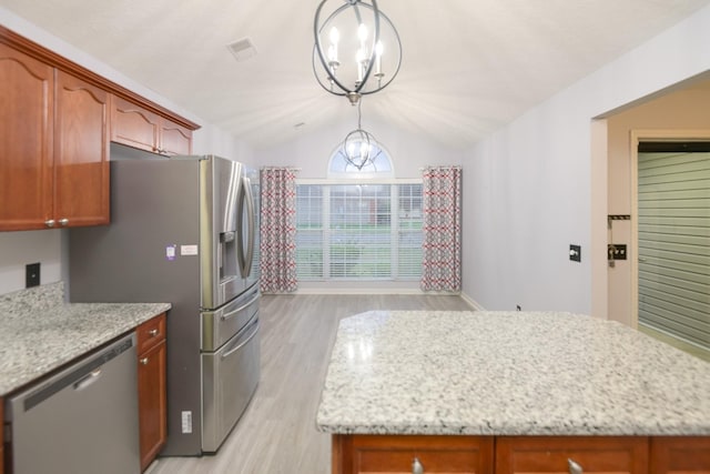 kitchen featuring vaulted ceiling, appliances with stainless steel finishes, pendant lighting, light stone countertops, and an inviting chandelier