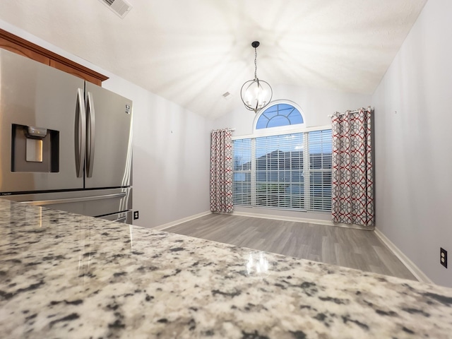 interior space with lofted ceiling, light hardwood / wood-style floors, stainless steel fridge with ice dispenser, and a notable chandelier