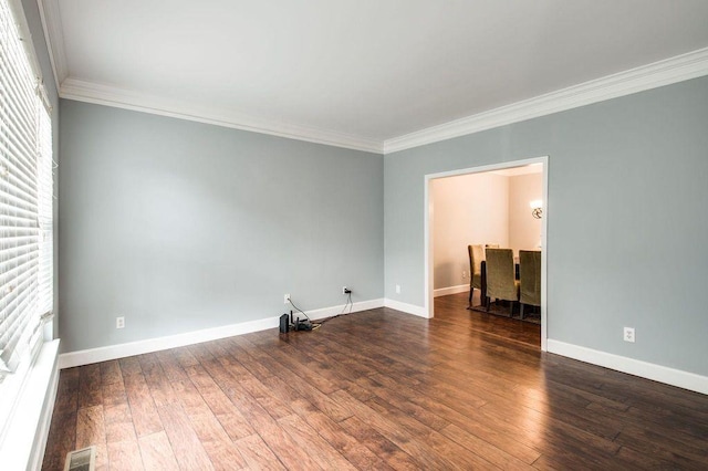 spare room with ornamental molding and dark hardwood / wood-style floors