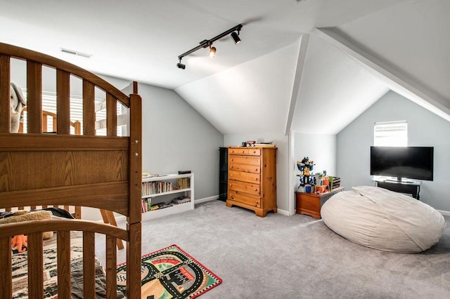 carpeted bedroom with lofted ceiling and rail lighting