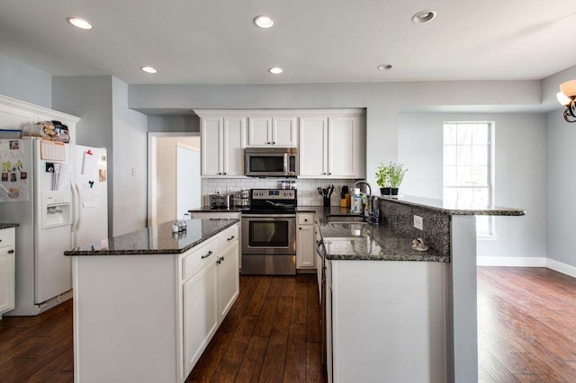 kitchen featuring white cabinets, stainless steel appliances, sink, and dark stone countertops