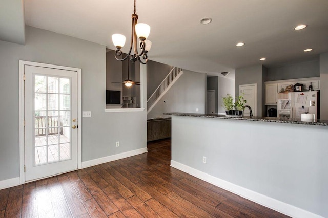 kitchen with pendant lighting, white cabinetry, dark stone counters, and fridge with ice dispenser