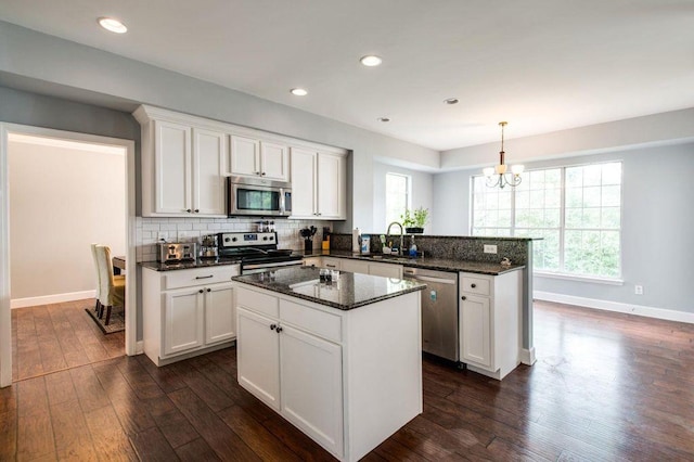 kitchen with hanging light fixtures, white cabinetry, appliances with stainless steel finishes, and sink