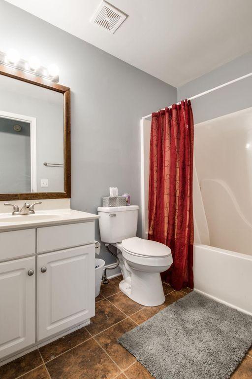 full bathroom featuring vanity, shower / bath combination with curtain, and toilet