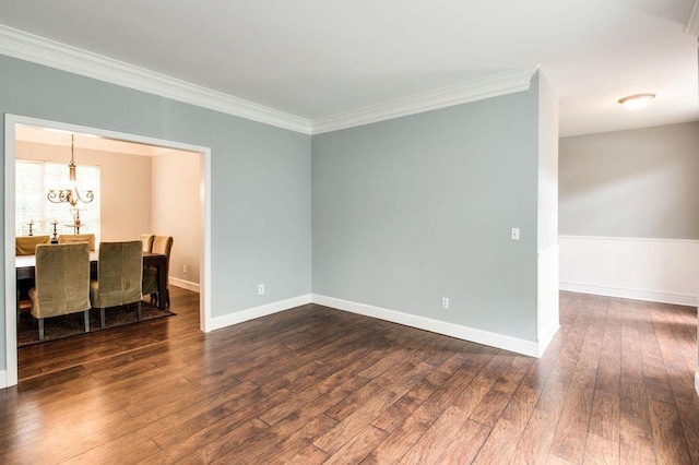 empty room featuring dark wood-type flooring, ornamental molding, and a notable chandelier