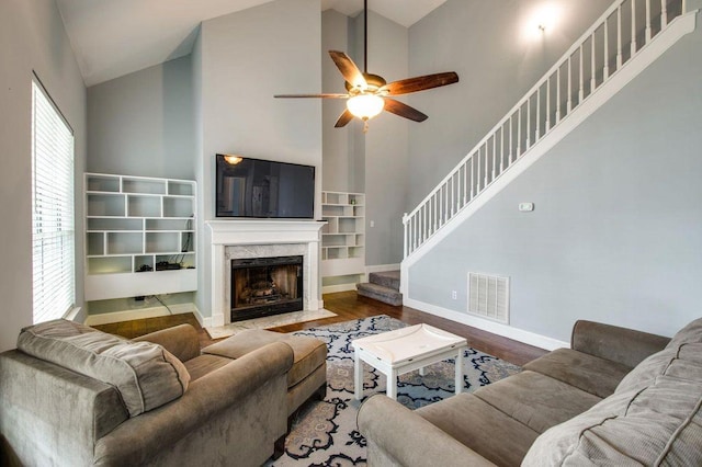 living room featuring hardwood / wood-style flooring, ceiling fan, high vaulted ceiling, and a fireplace