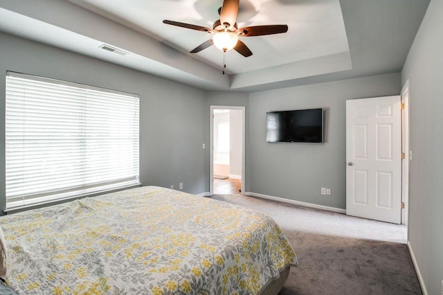 carpeted bedroom featuring a raised ceiling and ceiling fan