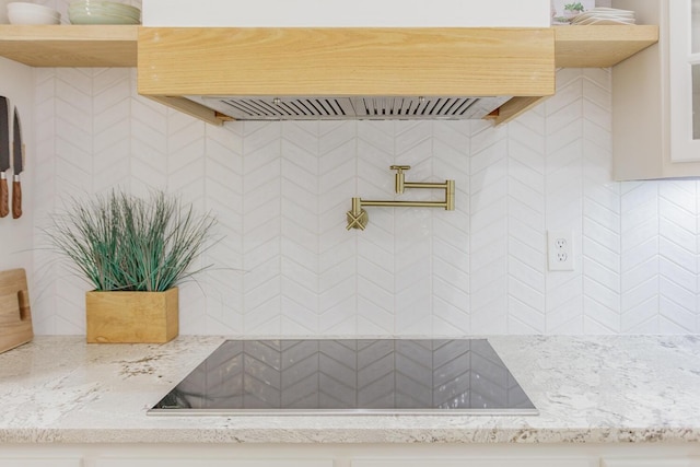 interior space featuring light stone counters, black electric stovetop, and backsplash