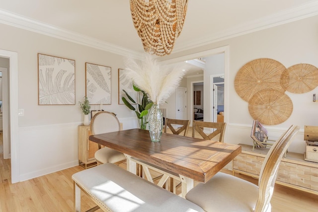 dining space with crown molding and light hardwood / wood-style flooring